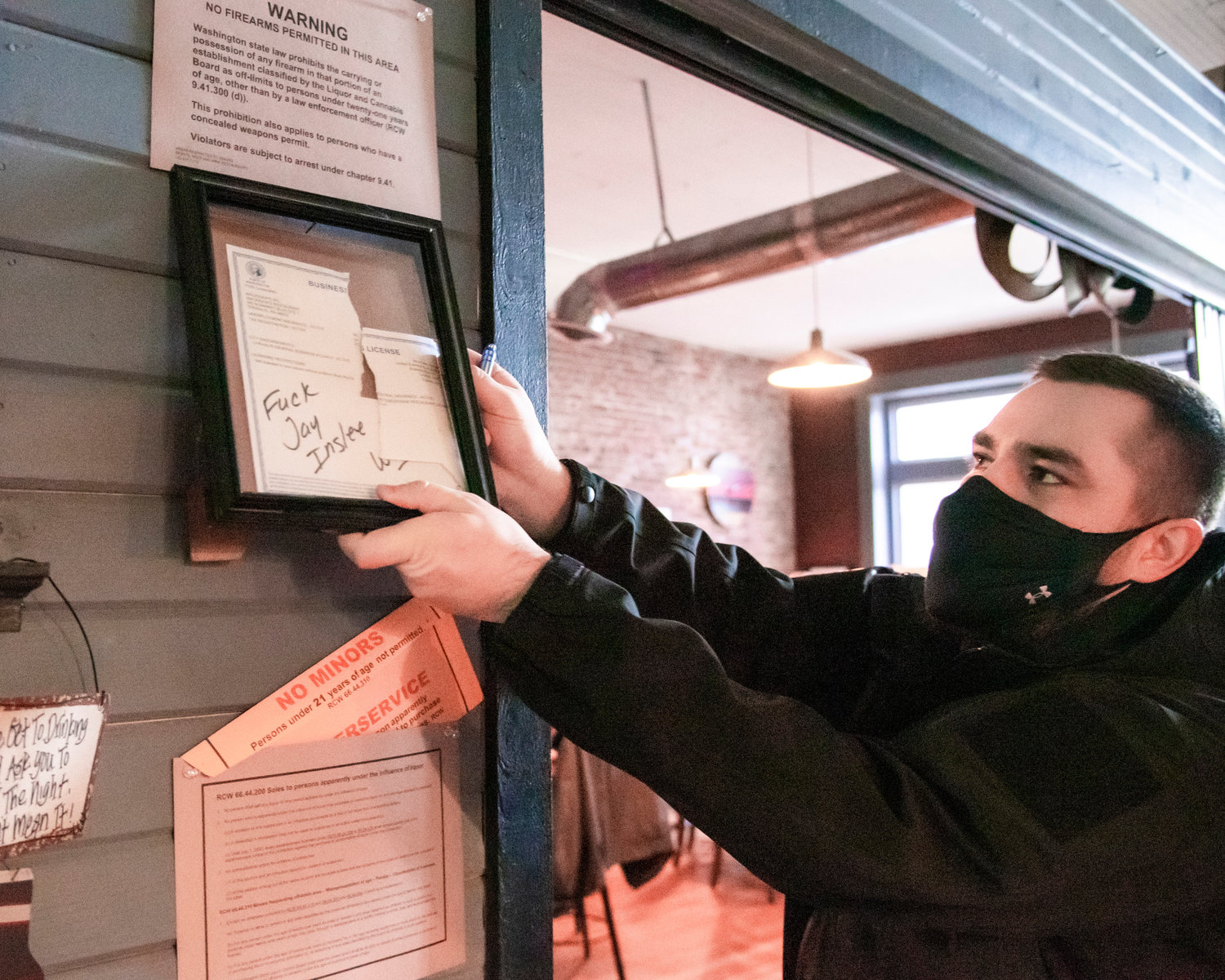 The Mackinaw's business license is removed from the wall Friday at Curious The Bar in Chehalis.
